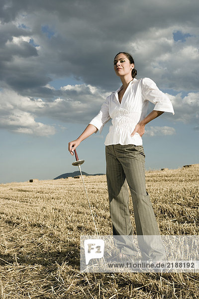 Woman standing with sword in wheat field.