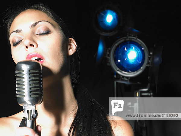 Close up of woman singing into microphone.