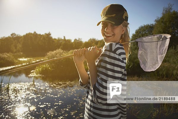 Junge Frau am Teich mit Fischernetz.