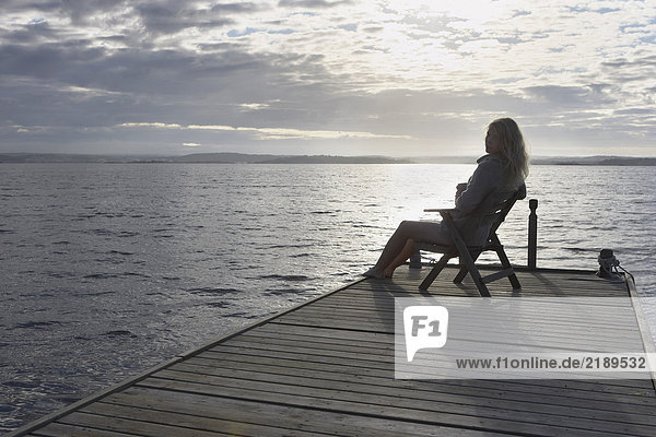 Young Woman relaxing on jetty.