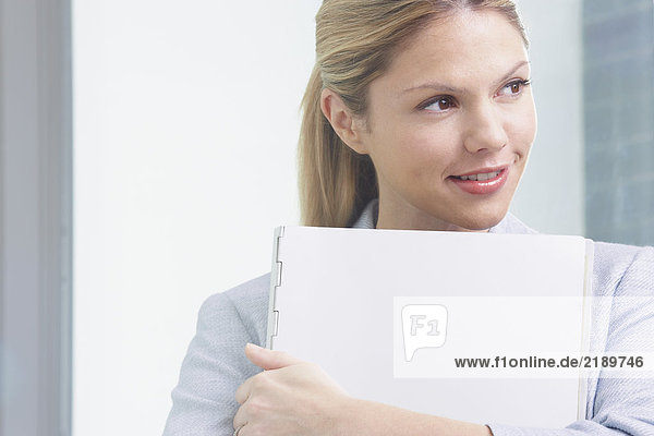 Young Business woman in office with file smiling.