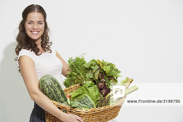 Junge Frau mit großem Korb mit Bio-Gemüse.