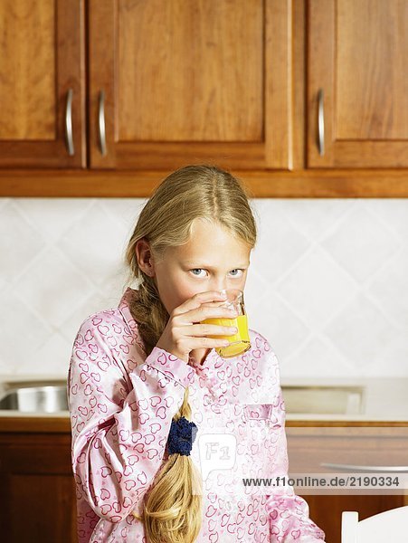Ein junges Mädchen in der Küche  das Orangensaft trinkt.
