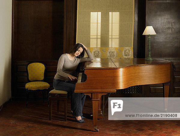 Junge Frau spielt Klavier  Ellbogen auf dem Klavier ruhend