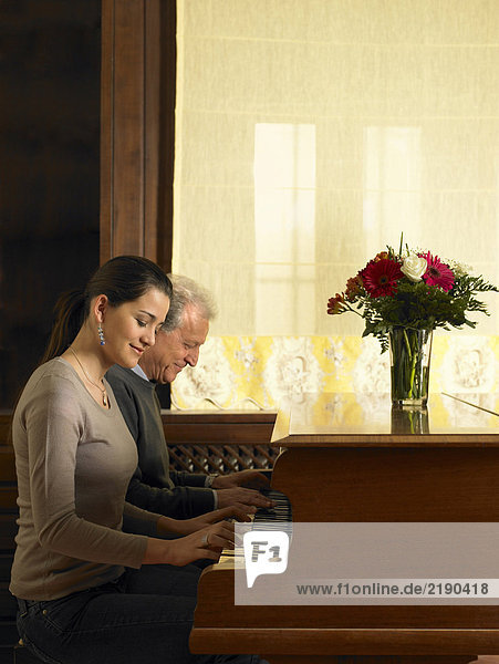 Senior Vater und Tochter im Duett am Klavier  lächelnd
