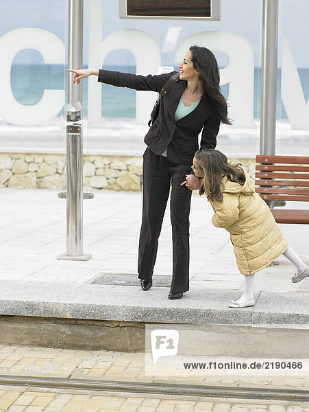 Frau und kleines Mädchen (6-8) warten an der Straßenbahnhaltestelle  Frau zeigt. Alicante  Spanien.