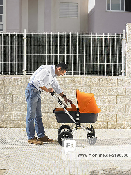 Vater schaut in den Kinderwagen auf dem Bürgersteig  Alicante  Spanien