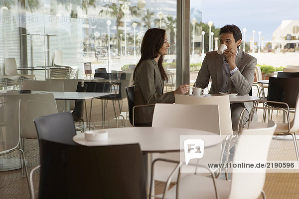 Geschäftsmann und Geschäftsfrau sitzen vor dem Café und trinken Kaffee. Alicante  Spanien.