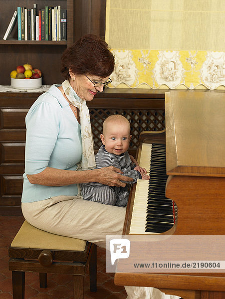 Senior Großmutter spielt Klavier mit Enkelkind (1-3 Monate)