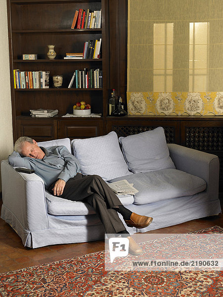 Senior man asleep on sofa in living room