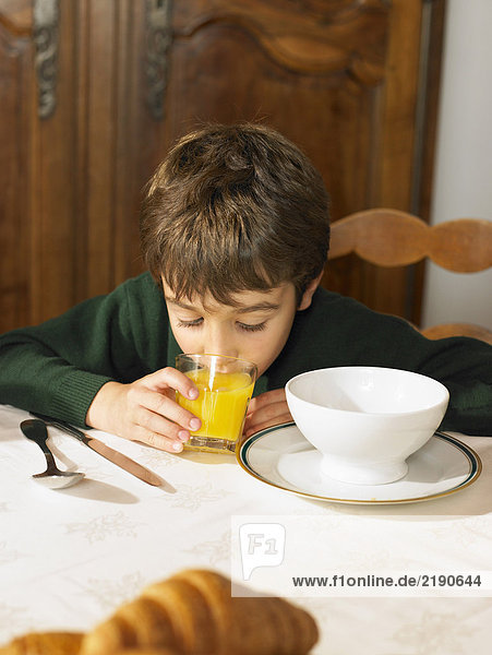 Boy (6-8) drinking orange juice at breakfast