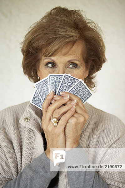 Seniorin mit Spielkarten über dem Gesicht  Nahaufnahme