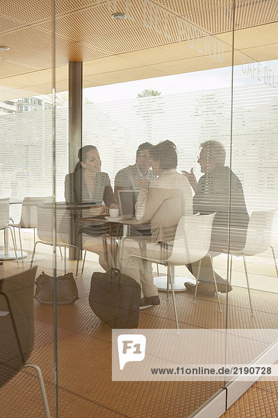 Two businessmen and two businesswomen having meeting in café  shot through window. Alicante  Spain.