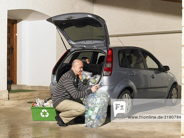Mann beim Verladen des Recyclings ins Auto