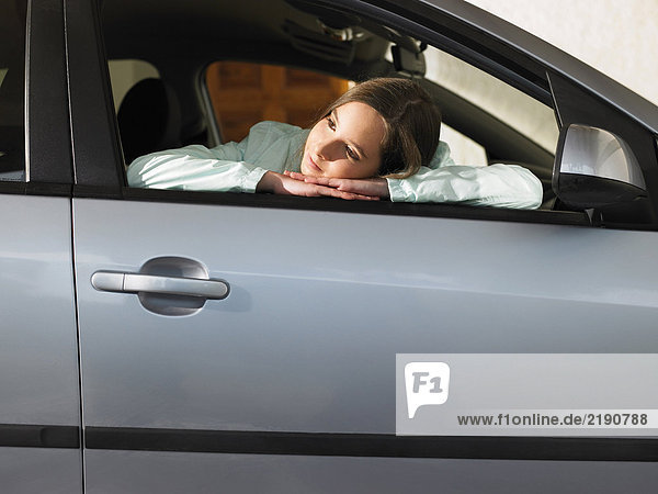 Girl (12-14) sitting in car  leaning on open window