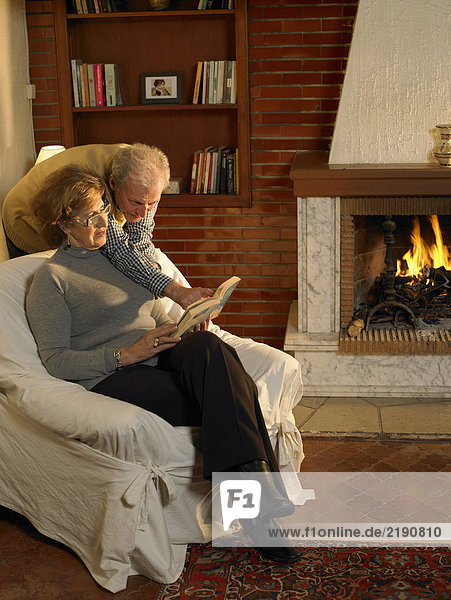 Seniorenpaar beim Betrachten des Buches im Wohnzimmer