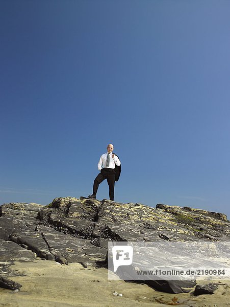 Businessman standing on rock.