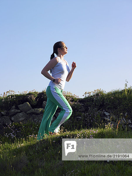 Eine Frau joggt einen Hügel hinauf.