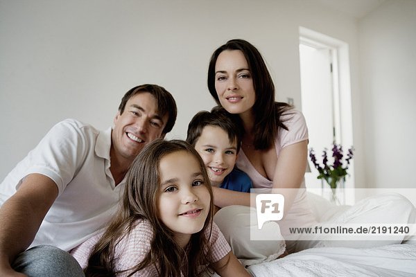 Portrait of a family sitting on a bed.