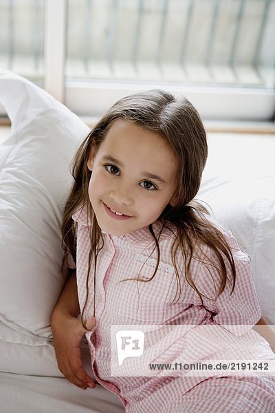 Portrait of a young girl laying on a bed.