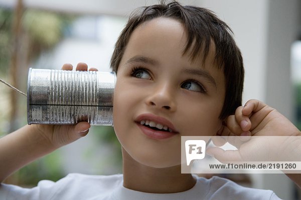 Boy using a tin can as a phone.