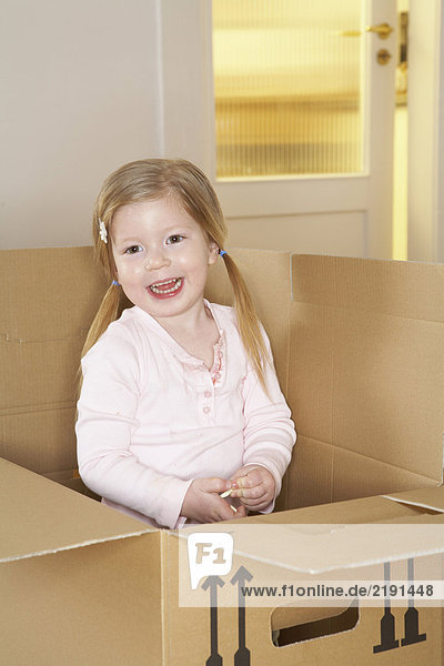 Girl (3-5) standing in cardboard box smiling  portrait