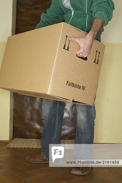 Young man carrying large cardboard box  low section
