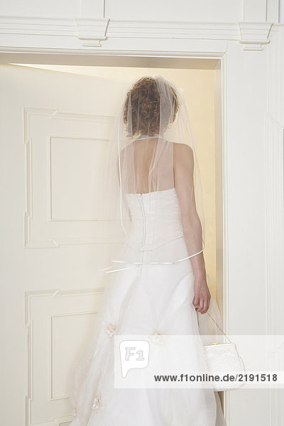 young bride standing in doorway  rear view