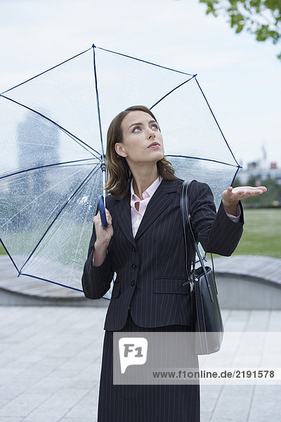 Geschäftsfrau mit Regenschirm bewaffnet  um zu prüfen  ob es nicht mehr regnet.