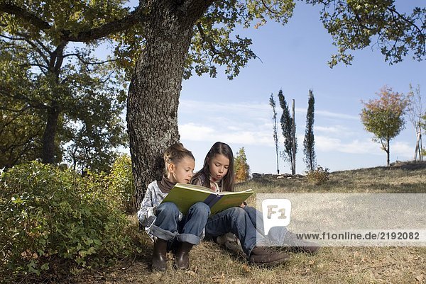 Two young girls reading a book.