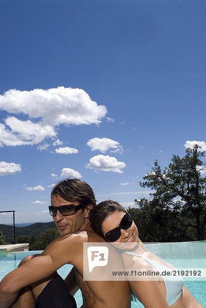 Couple sunbathing by a swimming pool