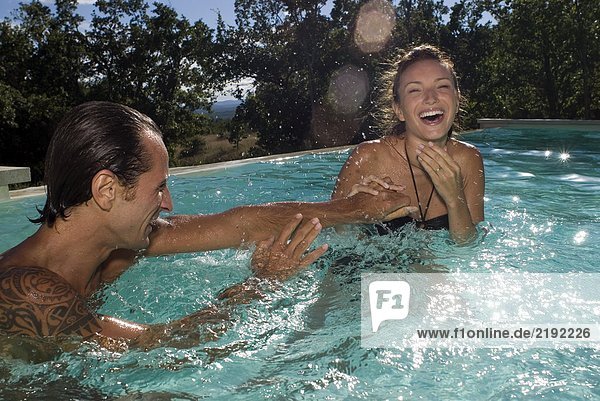 Couple playing with water in the swimming pool
