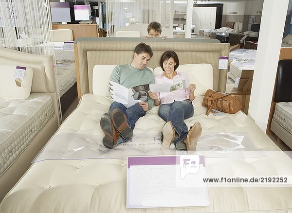Family looking at brochures on a bed.