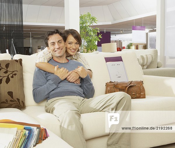 Smiling couple on sofa in furniture shop.