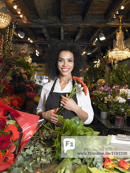 Junge Floristin bereitet Blumenstrauß im Geschäft vor  lächelnd  Portrait