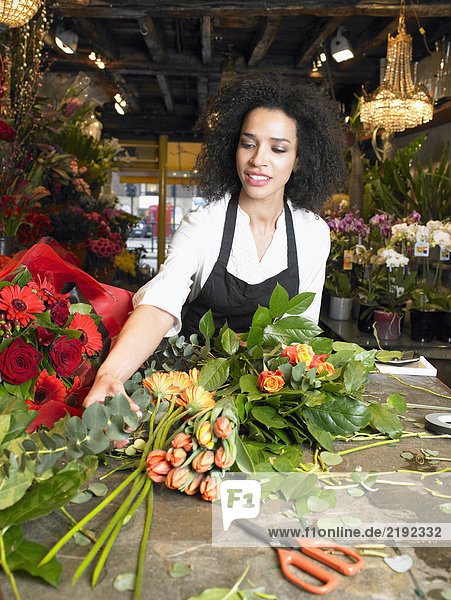 Junge Floristin bereitet Blumenstrauß im Geschäft vor  lächelnd