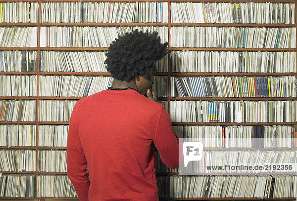 Mann beim Betrachten von CDs in den Regalen im Musikgeschäft  Rückansicht