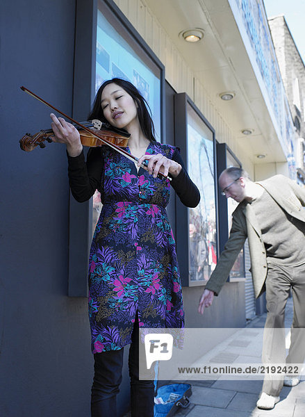 Mann spendet Geld an junge Frau  die Geige spielt