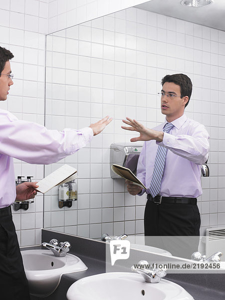 Mann beim Sprechen im Büro-Waschraumspiegel