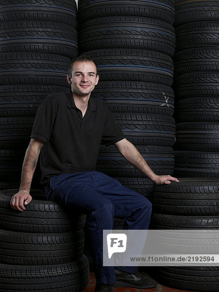 Mechaniker auf einem Reifenstapel sitzend