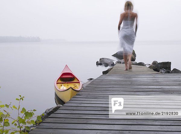 Eine Frau die auf einem Dock in der Nähe eines Bootes läuft.