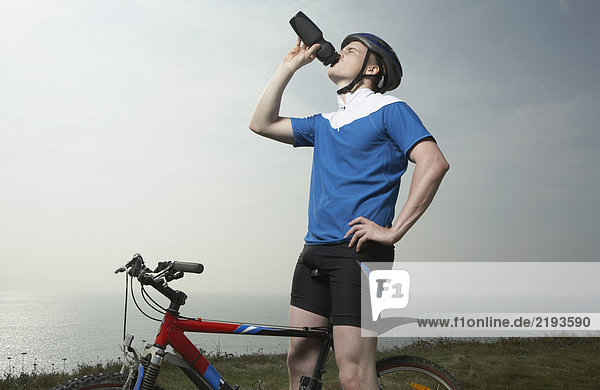 Ein männlicher Radfahrer trinkt.