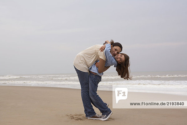 Mother embracing daughter (9-11) on beach  portrait