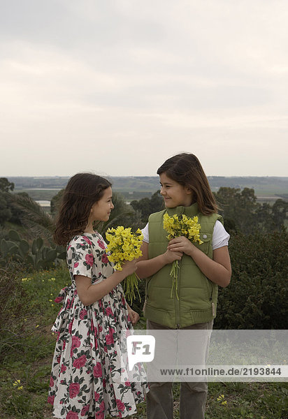 Two girls (5-8) holding bunches of flowers