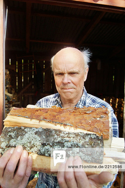 Älterer Mann mit Brennholz