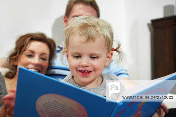 Children reading a book with their parents