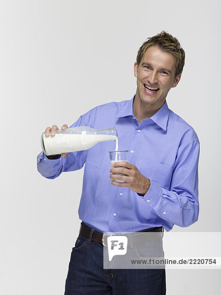 Junger Mann gießt Milch in ein Glas  Portrait