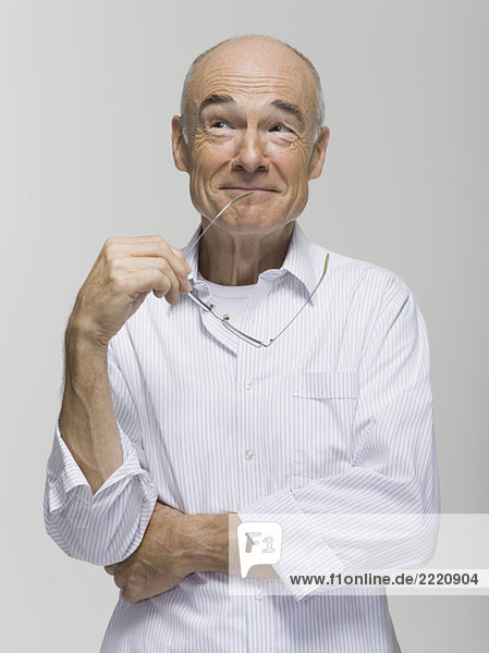 Senior man smiling  holding his spectacles  portrait