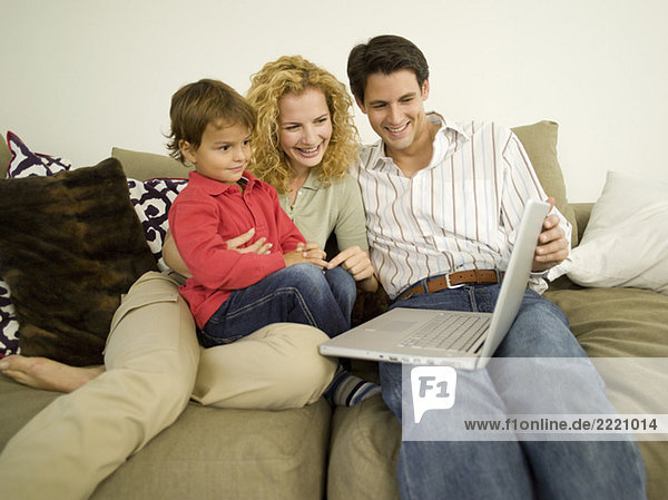 Young family in living room  father using laptop