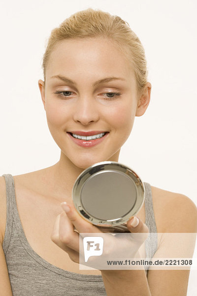 Woman looking at self in make-up mirror  portrait